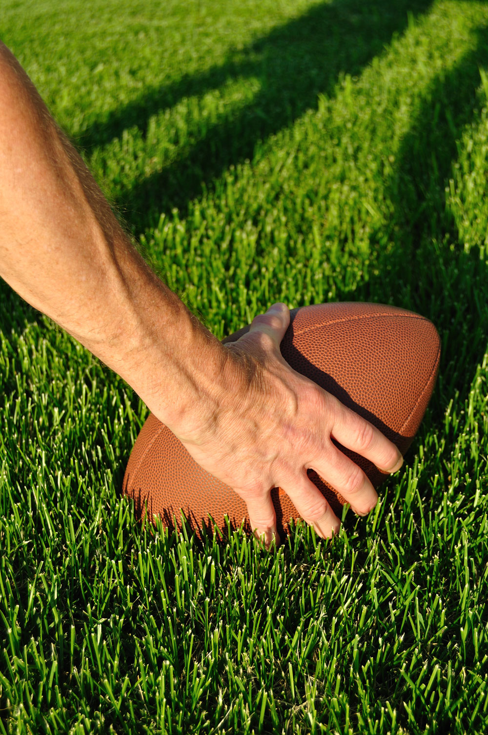 man holding a football on turf